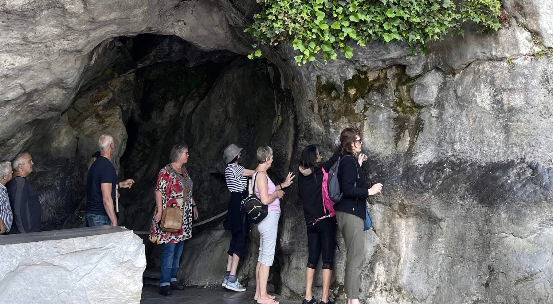 Pilgrims touching the rock of Massabielle Grotto Lourdes France